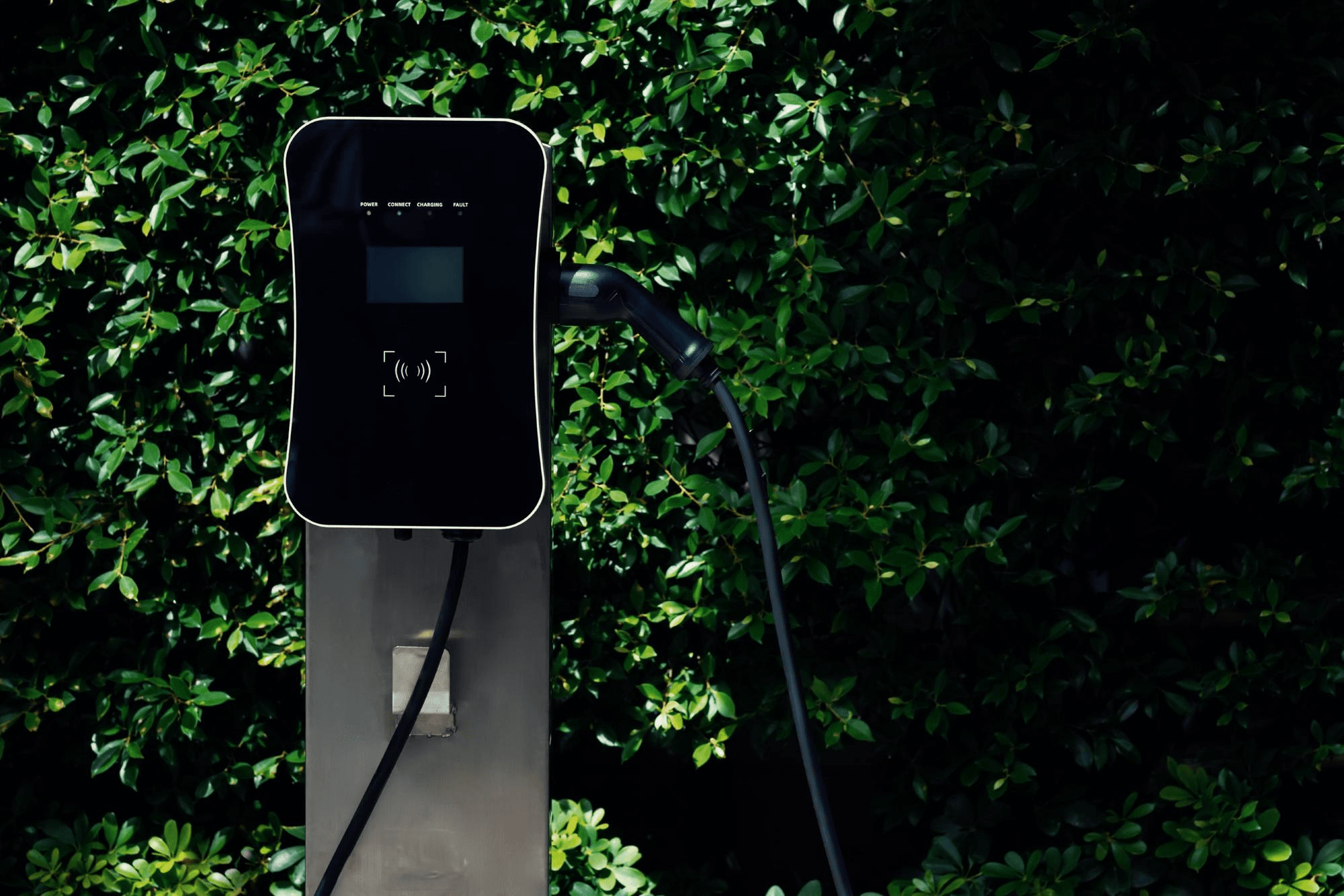Wall-mounted EV charger installed among greenery at a residential society